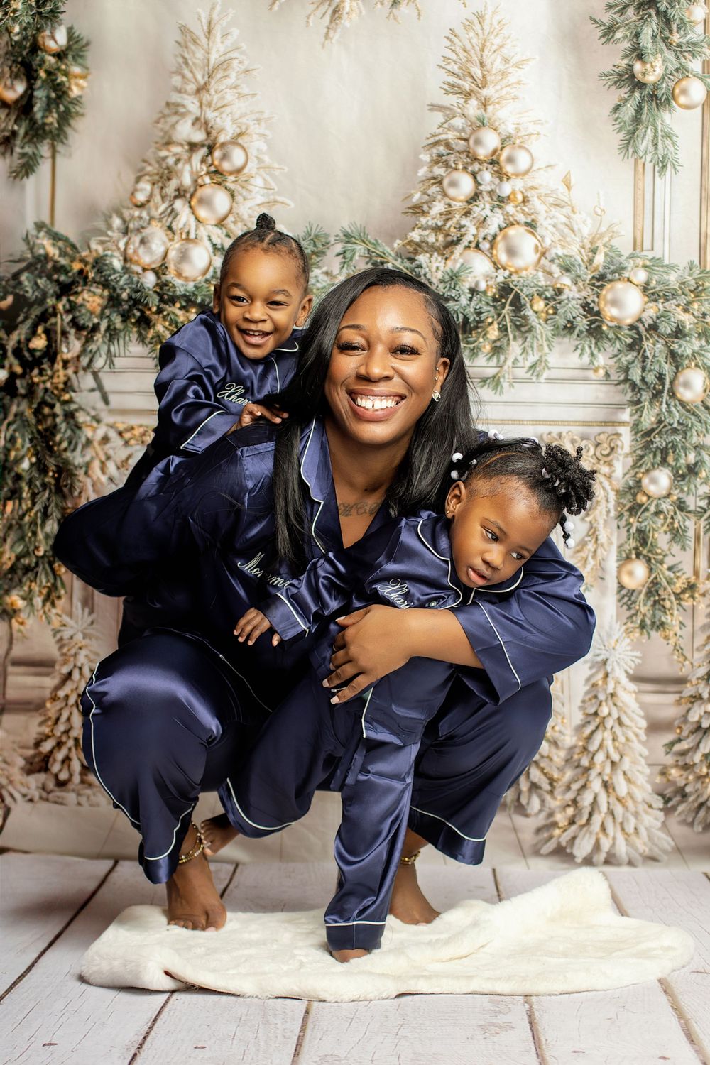 Playful family pose in matching navy sleepwear against elegant Christmas tree backdrop. at Vanessa Charlotte Photography studio