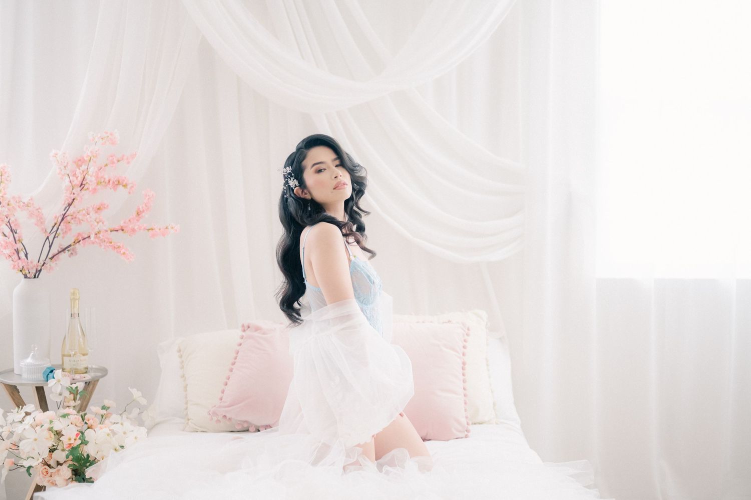 A figure in white flowing fabric kneels gracefully against a light backdrop in a minimalist artistic photo series.