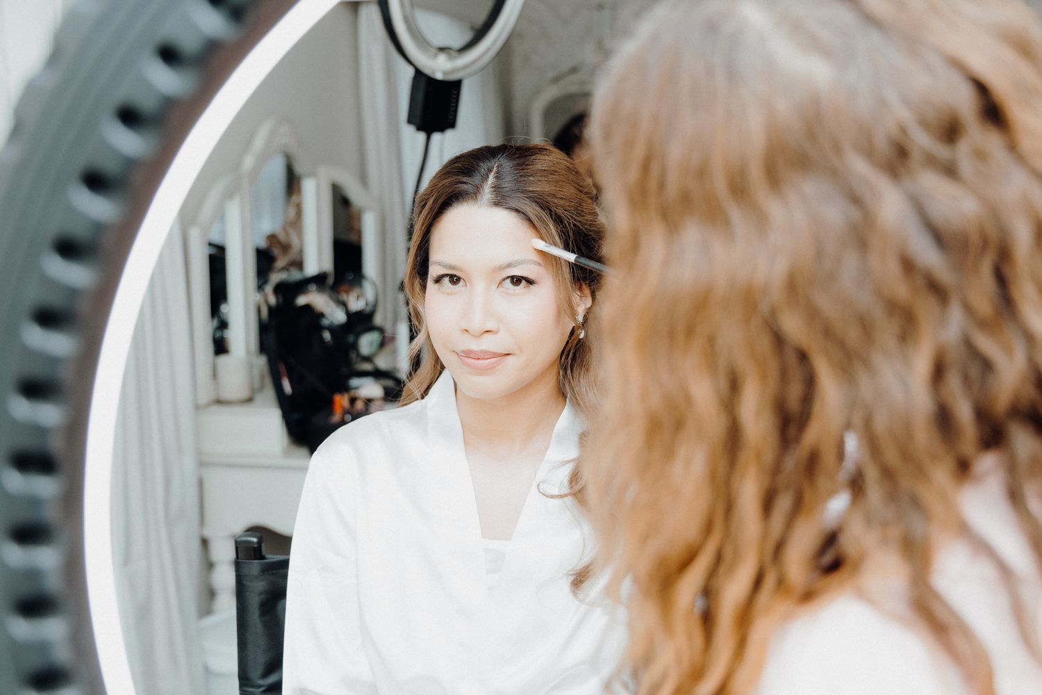 A mirror reflection shows someone getting ready in a white outfit with their hair styled for an event.