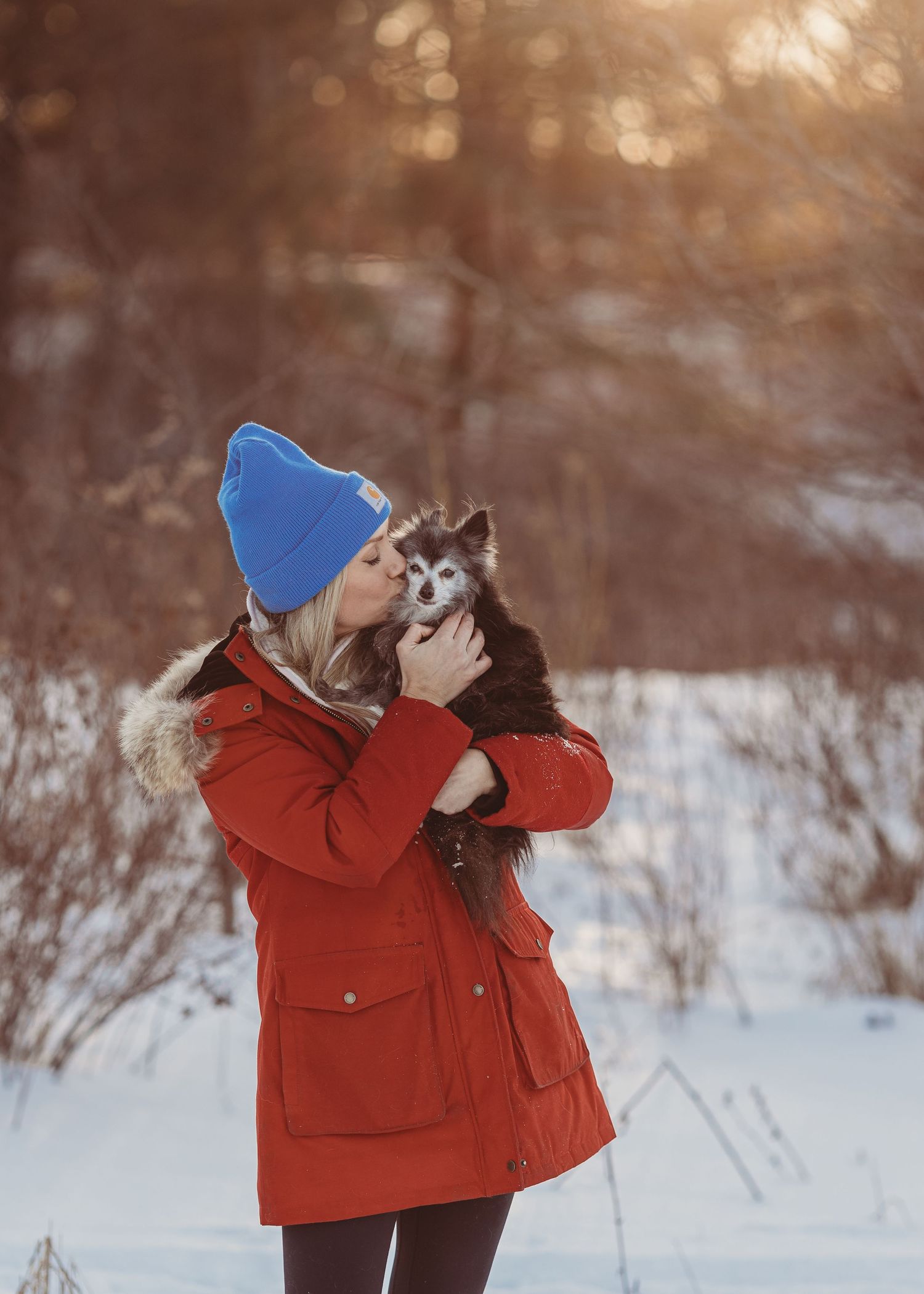 woman kissing her small dog