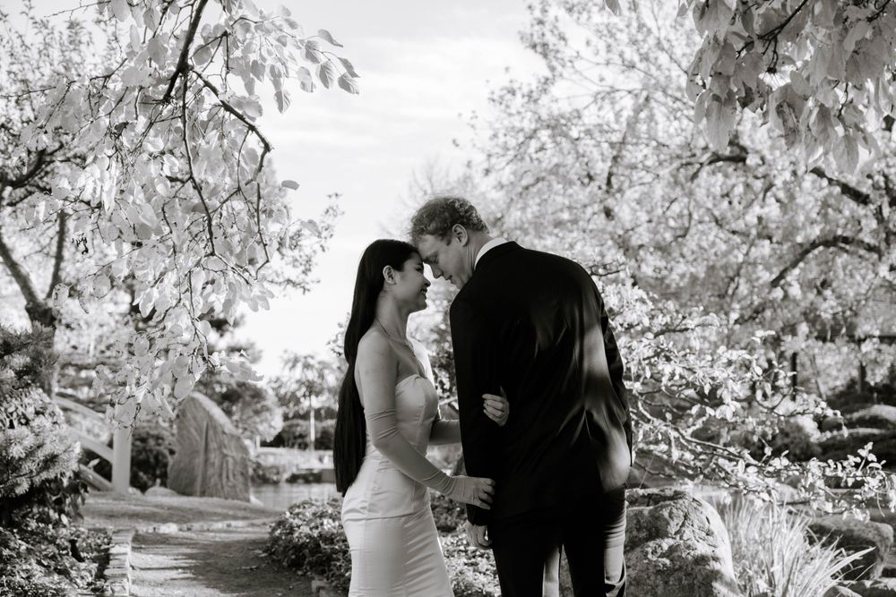 A romantic black and white wedding photo with snow-covered branches in a beautiful garden setting.