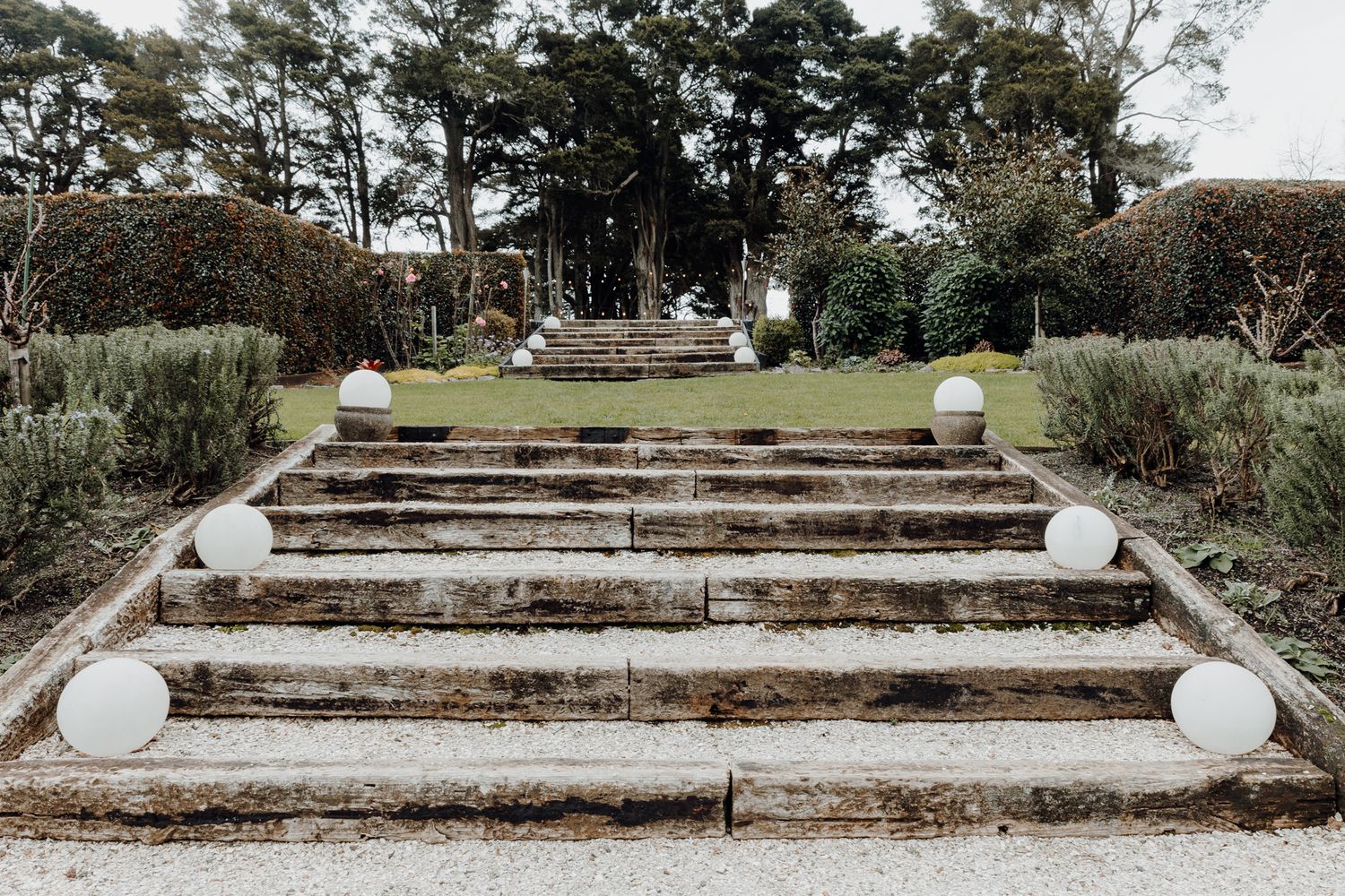 Stone steps leading up to a garden venue decorated with white spherical lanterns.