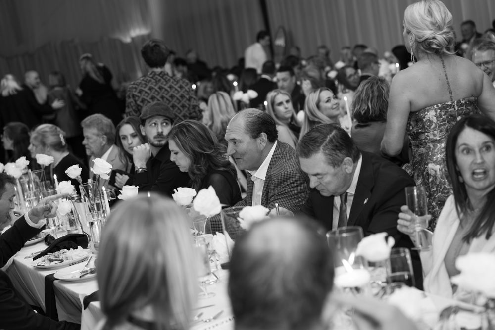 Black and white photo of guests seated at elegant tables during a formal wedding reception or dinner event.