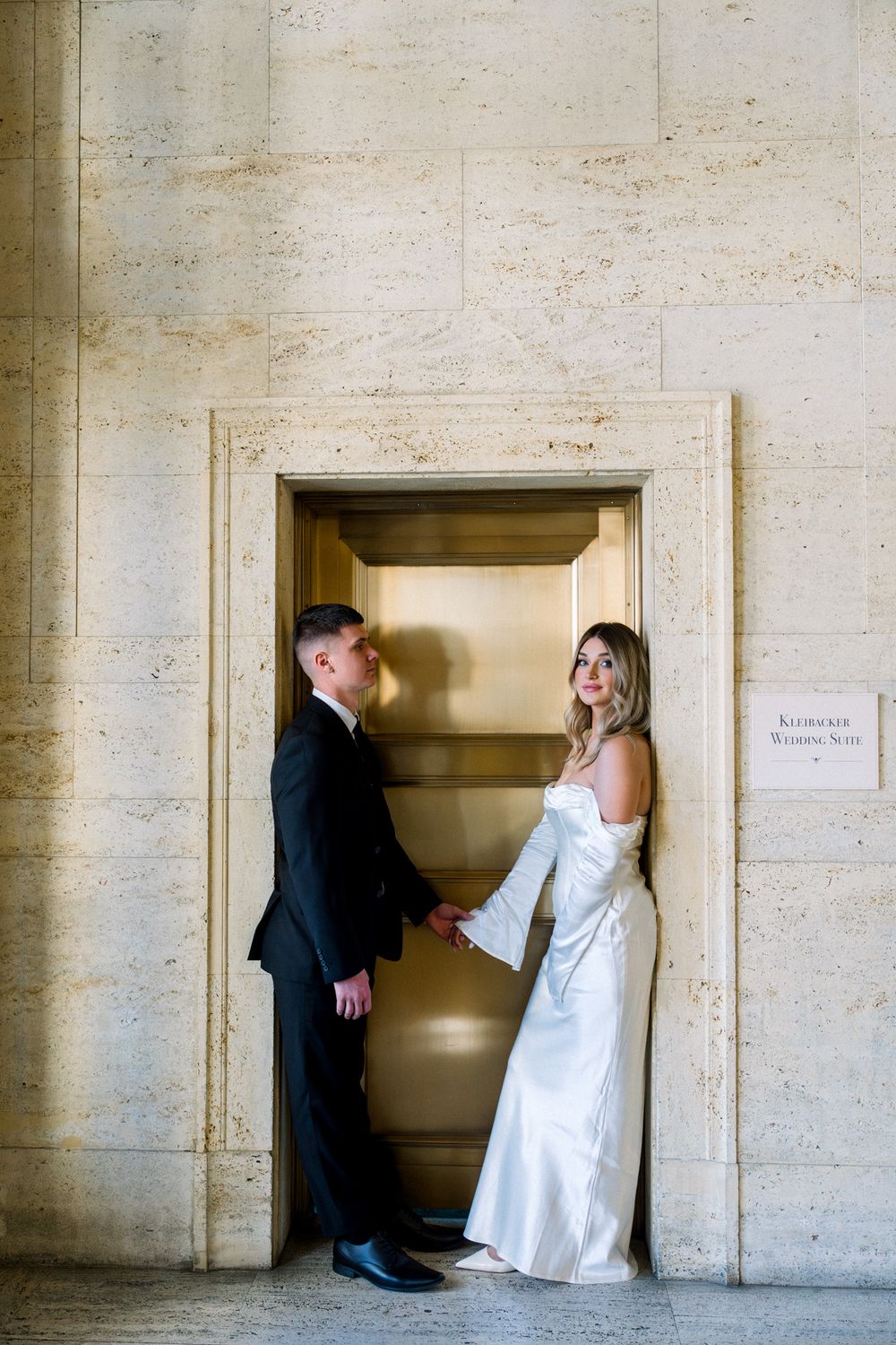 Formal couple posing in elegant doorway of stone building.
