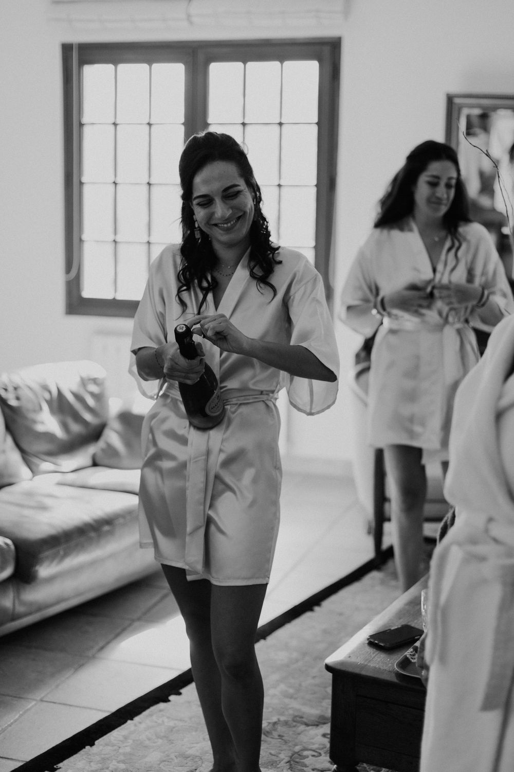 Getting ready scene with women in white robes preparing for wedding day.