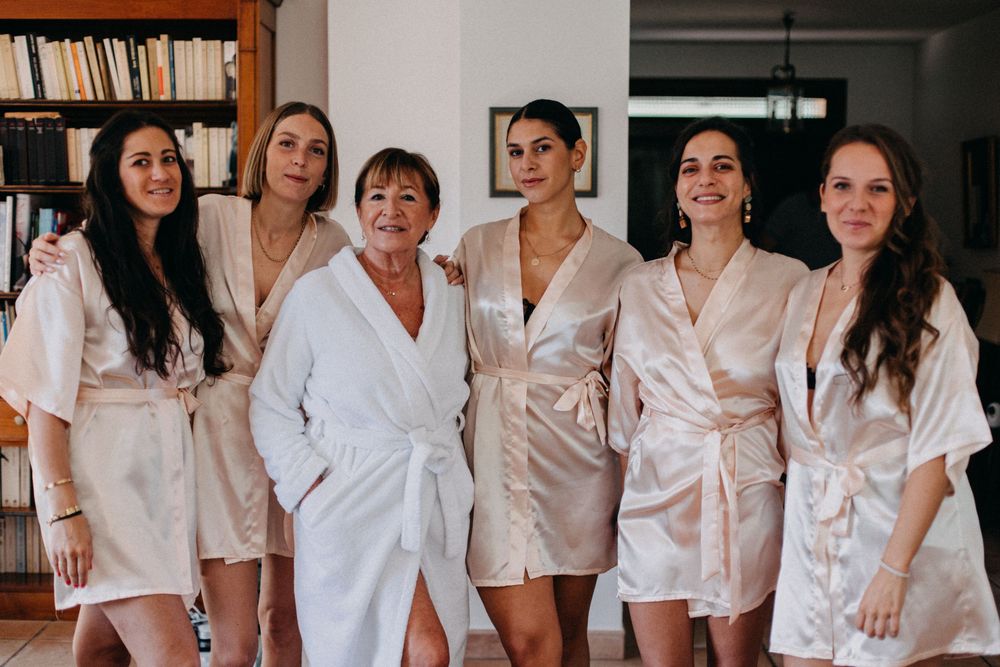 A group in matching silk robes poses together in an indoor setting with bookshelves in the background.