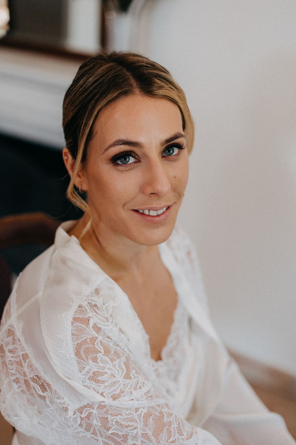Close-up portrait of a bride wearing a delicate lace robe during wedding preparations.