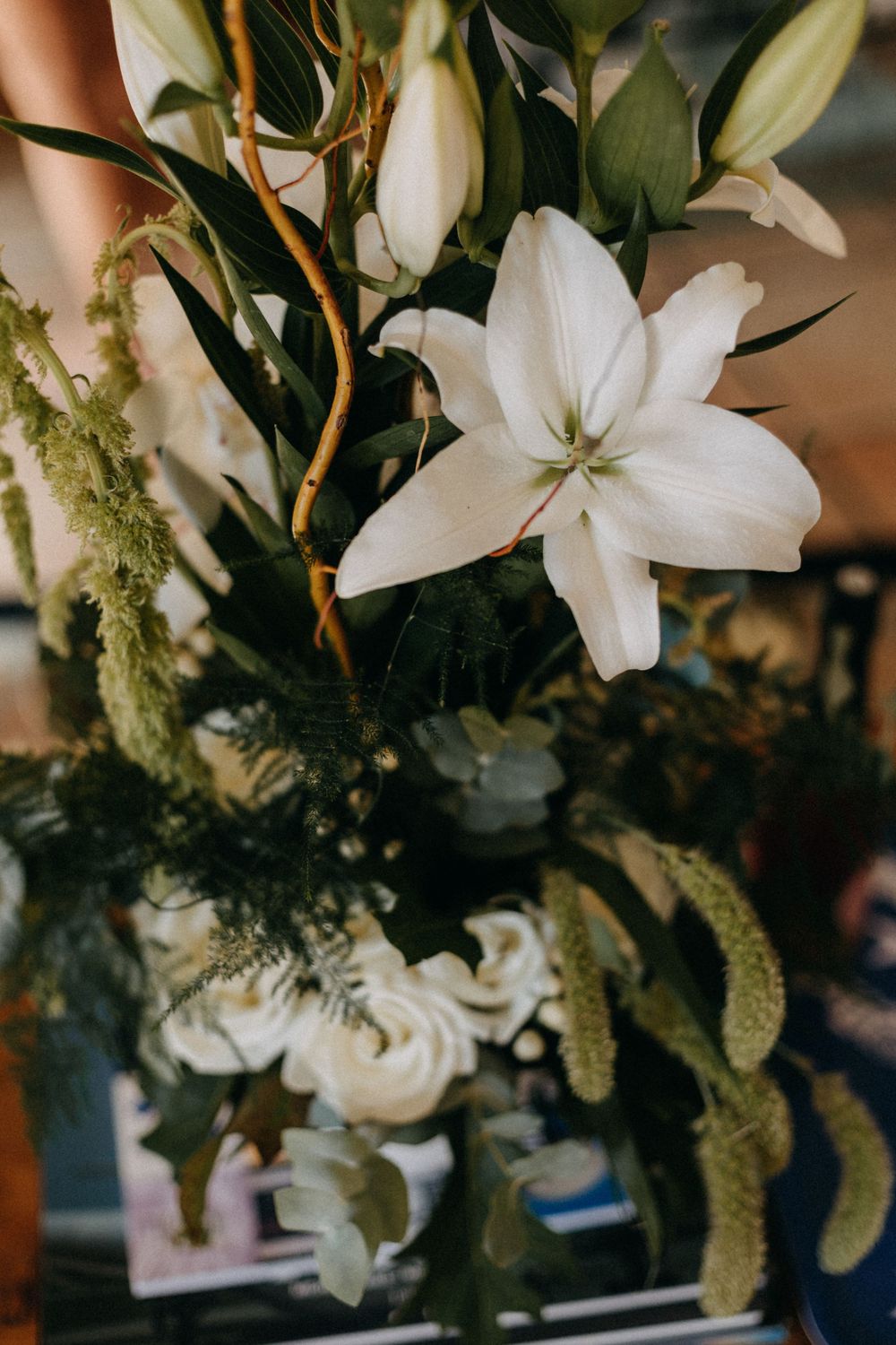White lily and greenery in moody wedding floral arrangement.