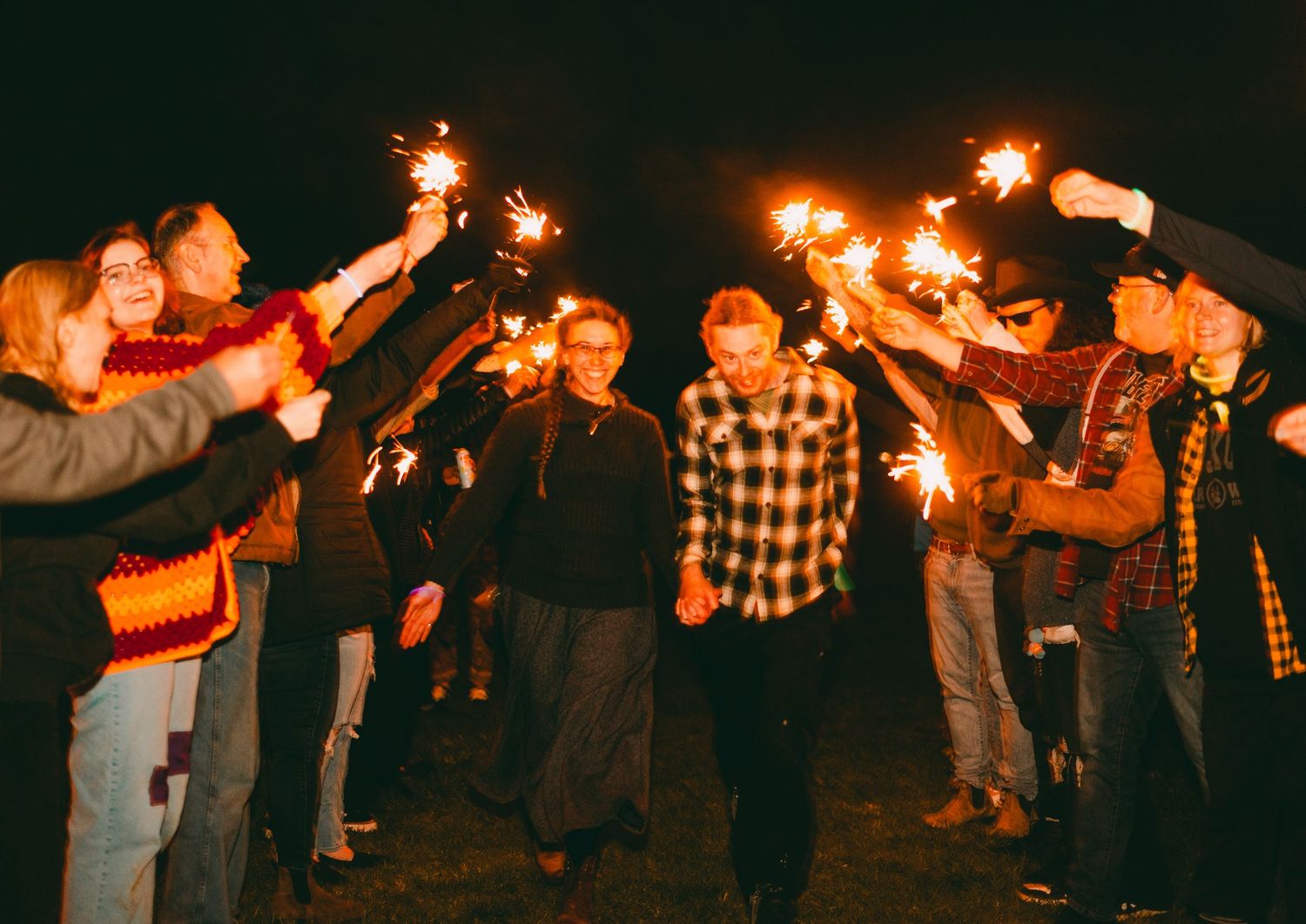 Couple runs through sparklers at relaxed bonfire wedding reception