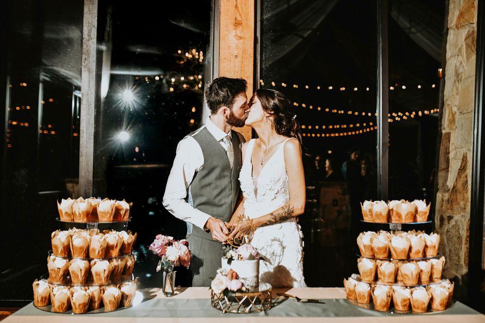 Bride holding the gold cake cutter set as the groom helps guide her hand.