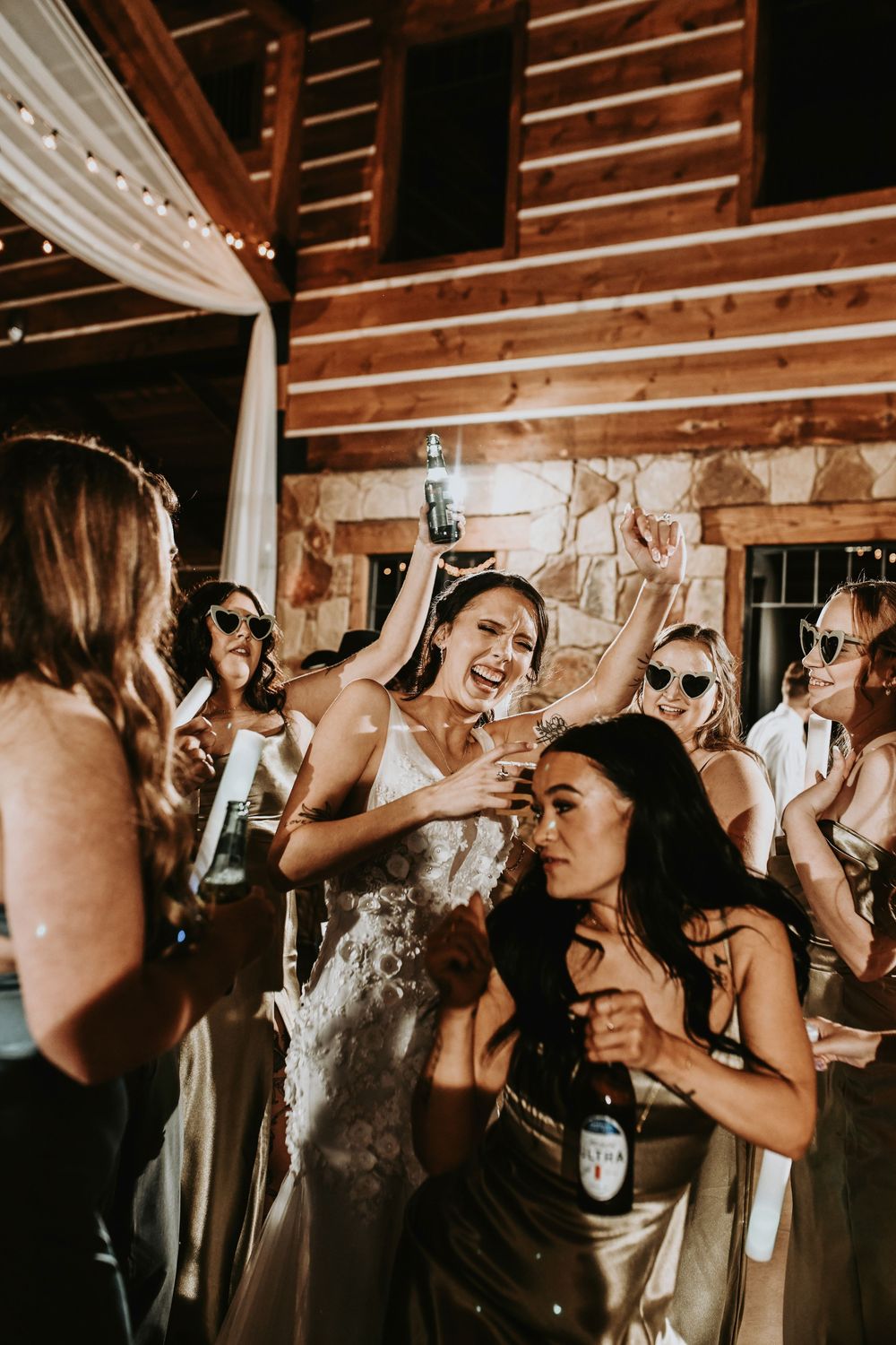 Bridesmaids and groomsmen dancing in a circle, throwing their hands up and celebrating in style.