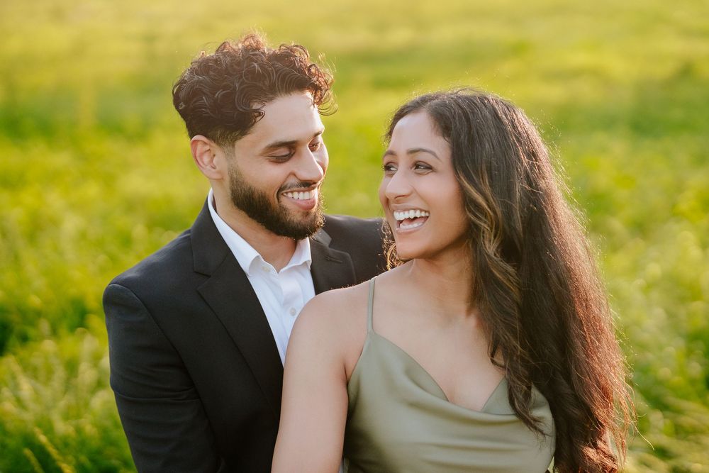 Happy couple sharing a joyful moment together in a sunlit meadow at golden hour.
