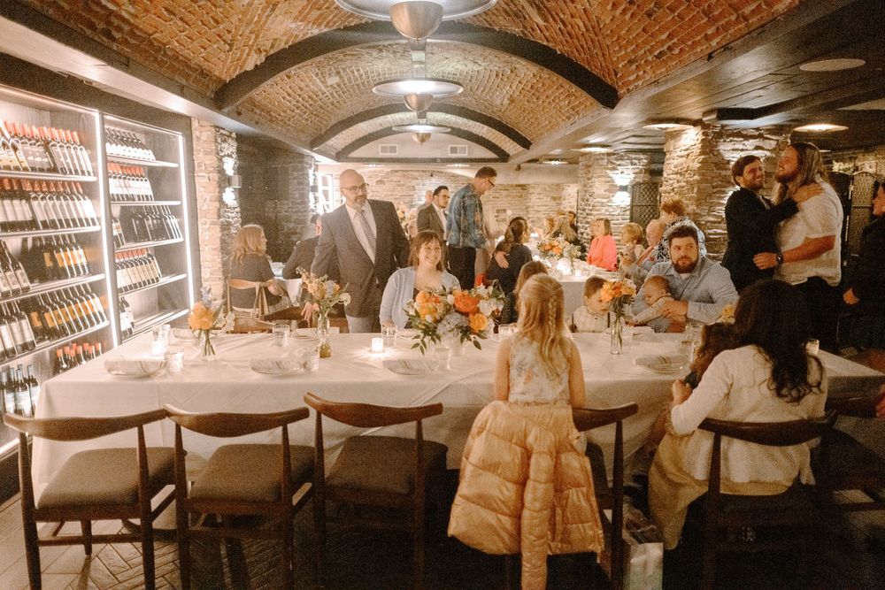Elegant dinner gathering in a rustic wine cellar with vaulted brick ceilings and ambient lighting.