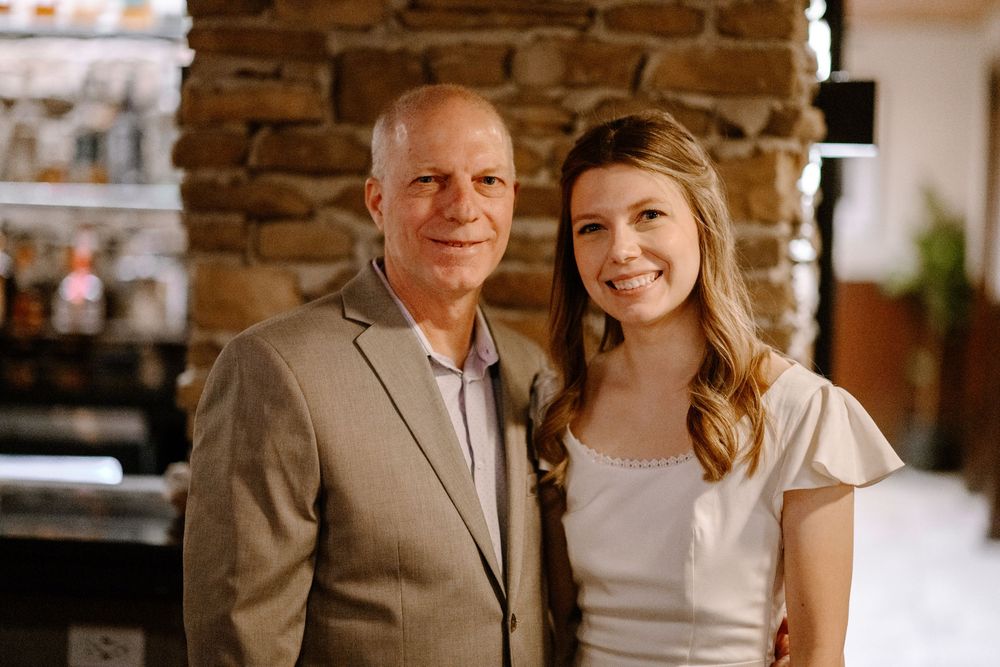 Couple posing together at a rustic venue with exposed brick wall.