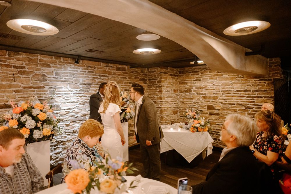 Romantic wedding reception in rustic cellar venue with exposed stone walls and overhead lighting.