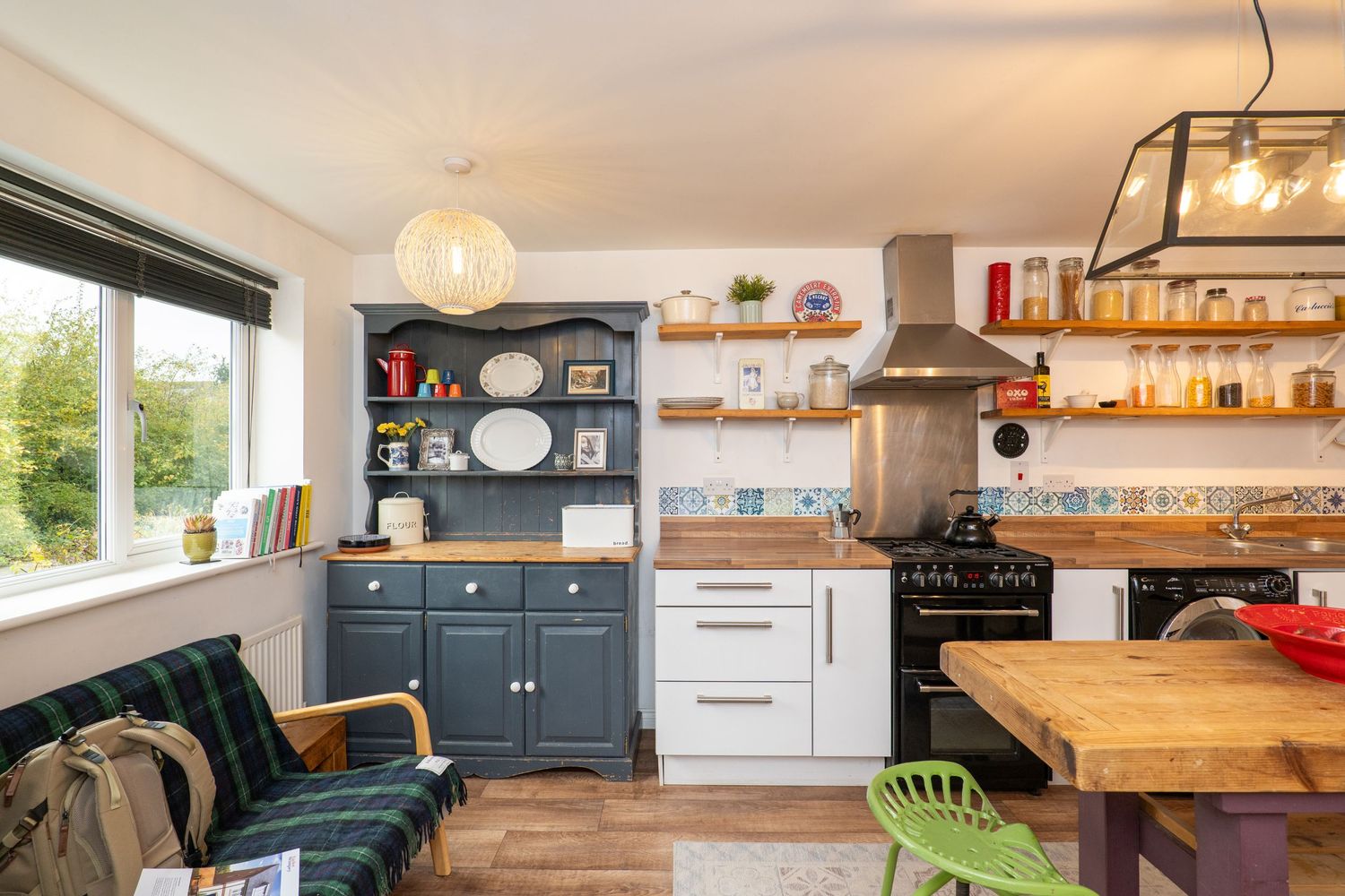 Modern rustic kitchen with wooden shelving, and dining area featuring natural lighting.