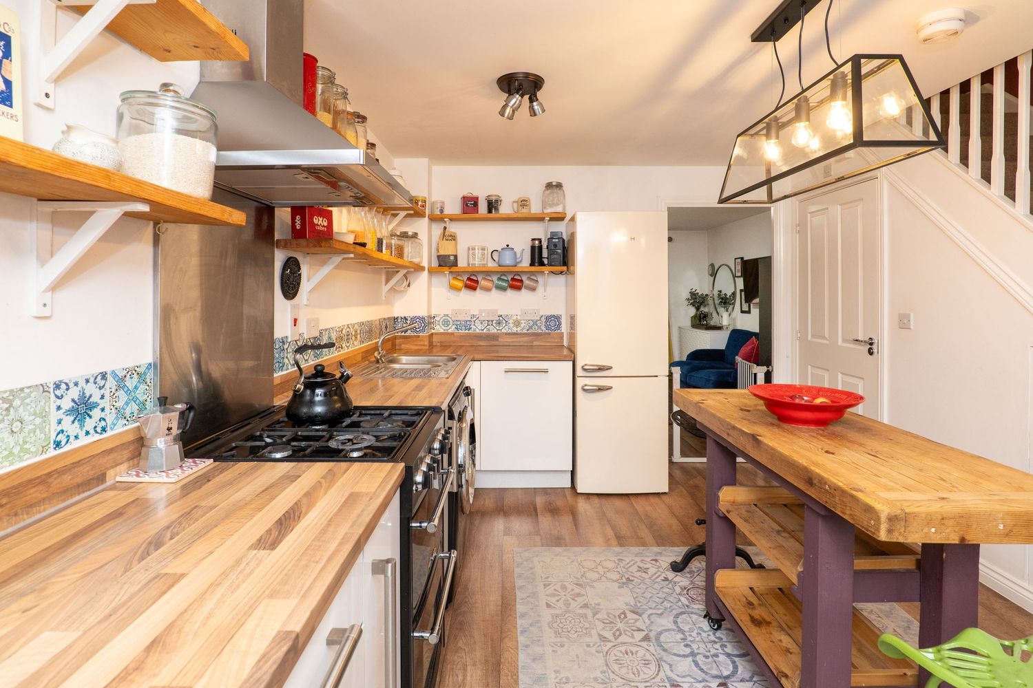 Galley kitchen with butcher block countertops, open shelving, and industrial pendant lighting.