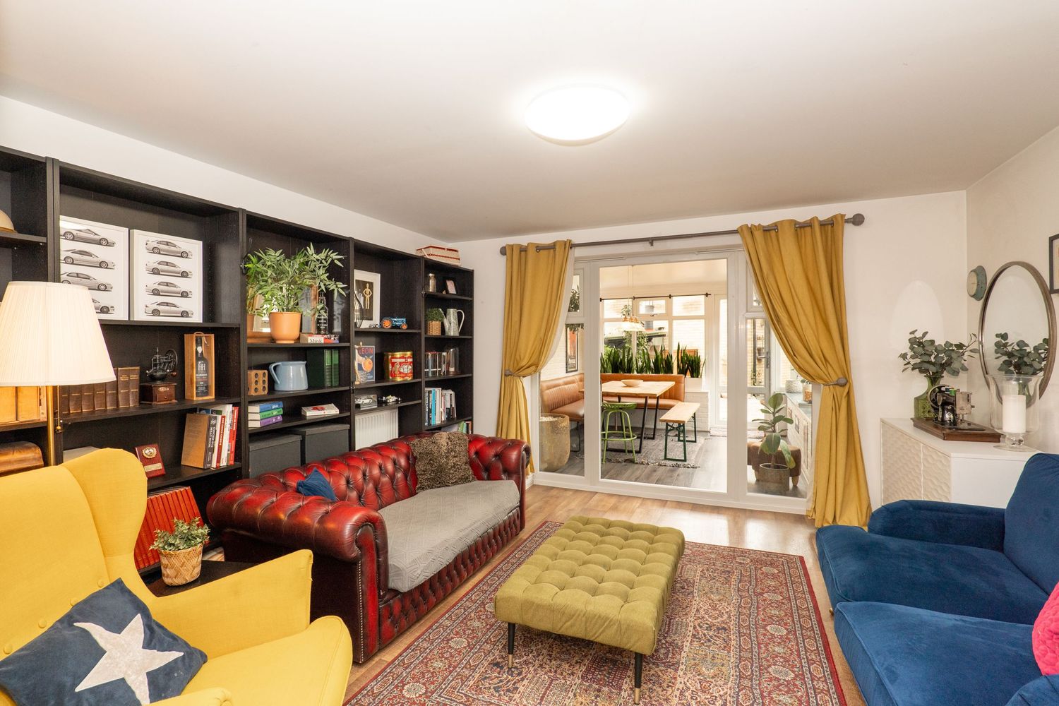 Cozy living room with colorful furniture, built-in bookshelves and yellow curtains.