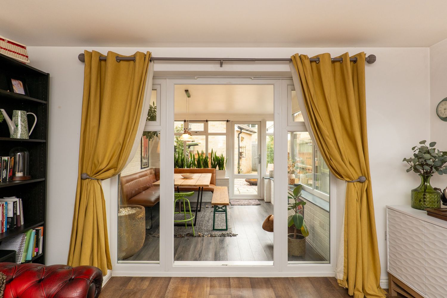 Living room with mustard yellow curtains framing glass doors and built-in bookshelves.