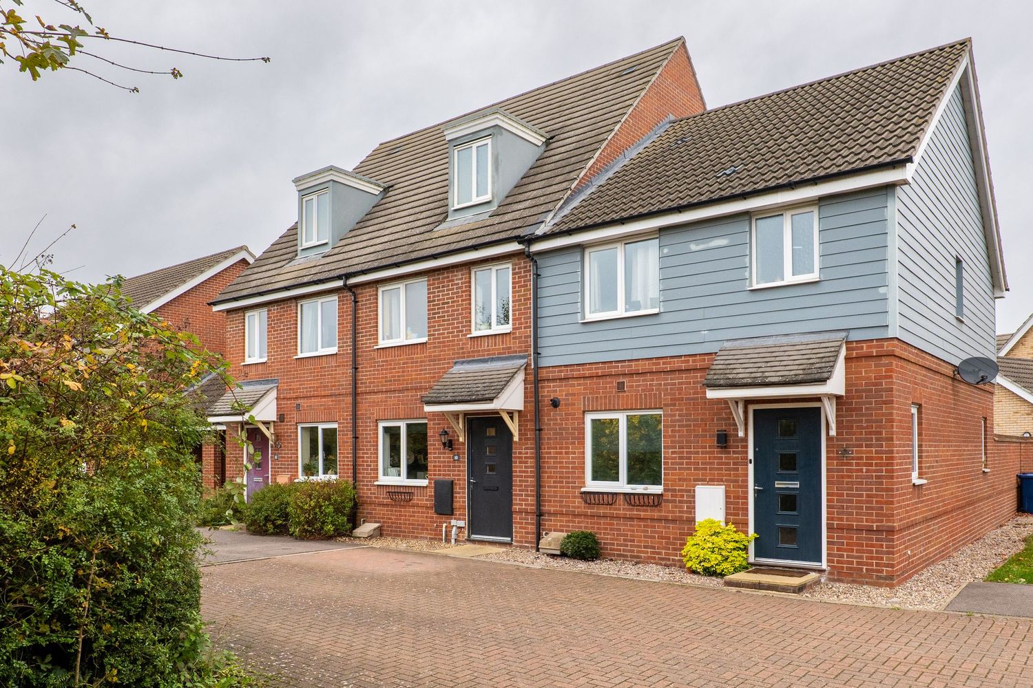Row of modern townhouses with red brick and grey cladding exteriors.