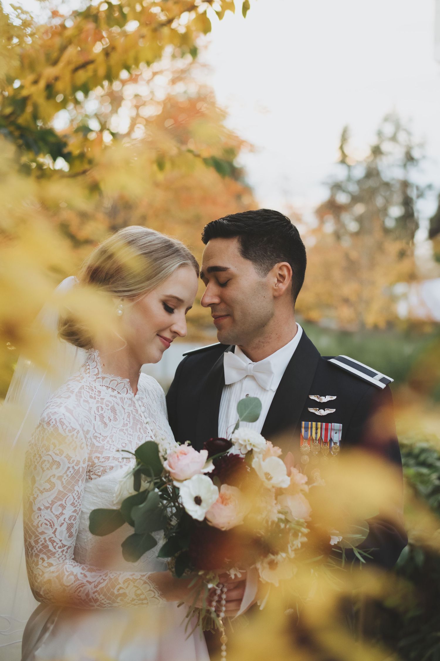 An intimate autumn wedding portrait framed by golden leaves.