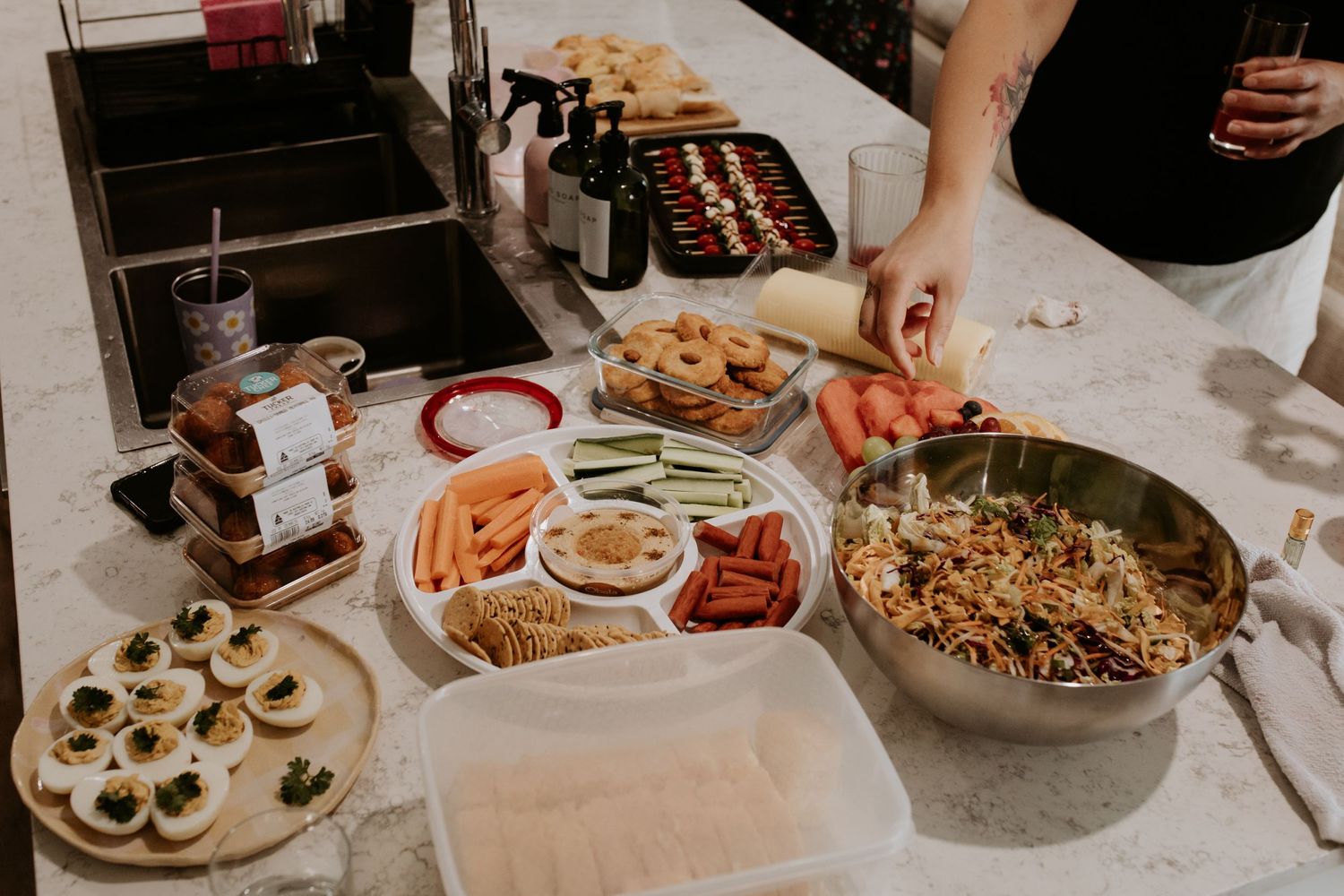 Various party appetizers and snacks laid out on a table including sushi rolls, vegetable sticks, and a large pan of mixed food.