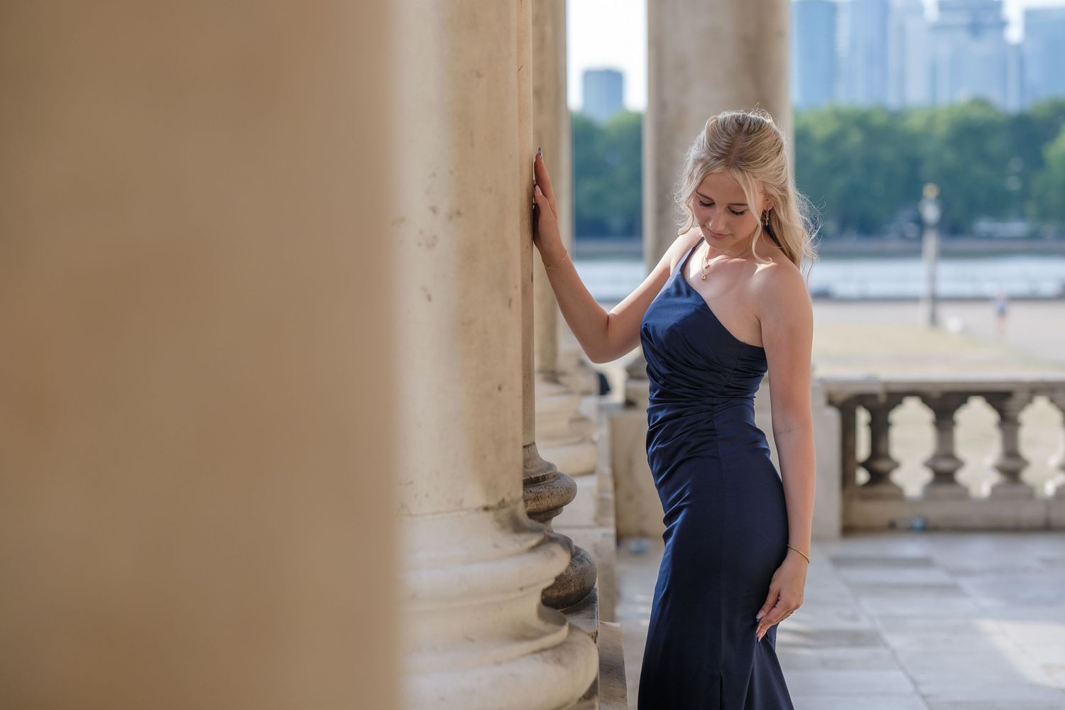 A series of professional portraits of someone wearing a formal navy dress in a classic architectural setting.