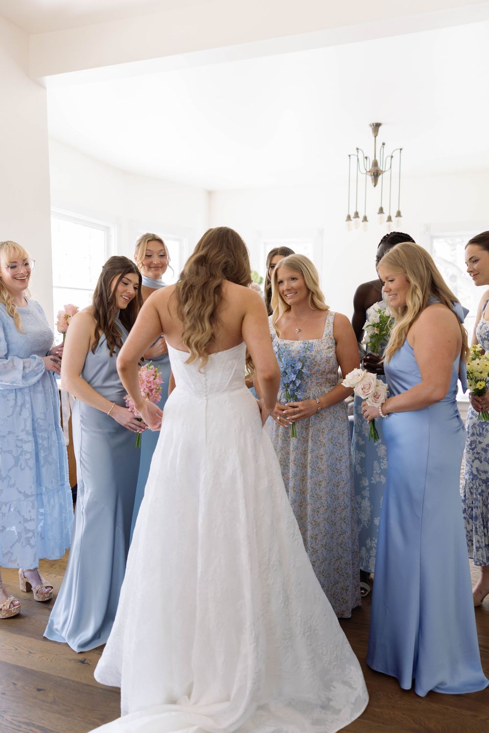 Bridesmaids in light blue dresses share emotional moments with the bride in white during a wedding celebration.
