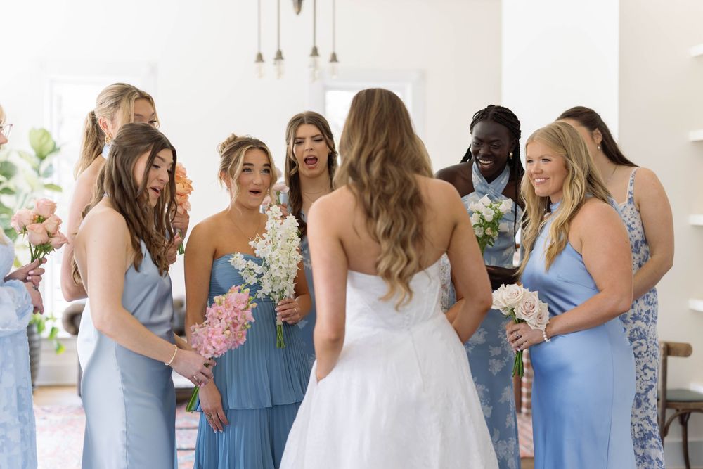 A group in light blue bridesmaid dresses and a white wedding gown gather at a wedding ceremony venue.