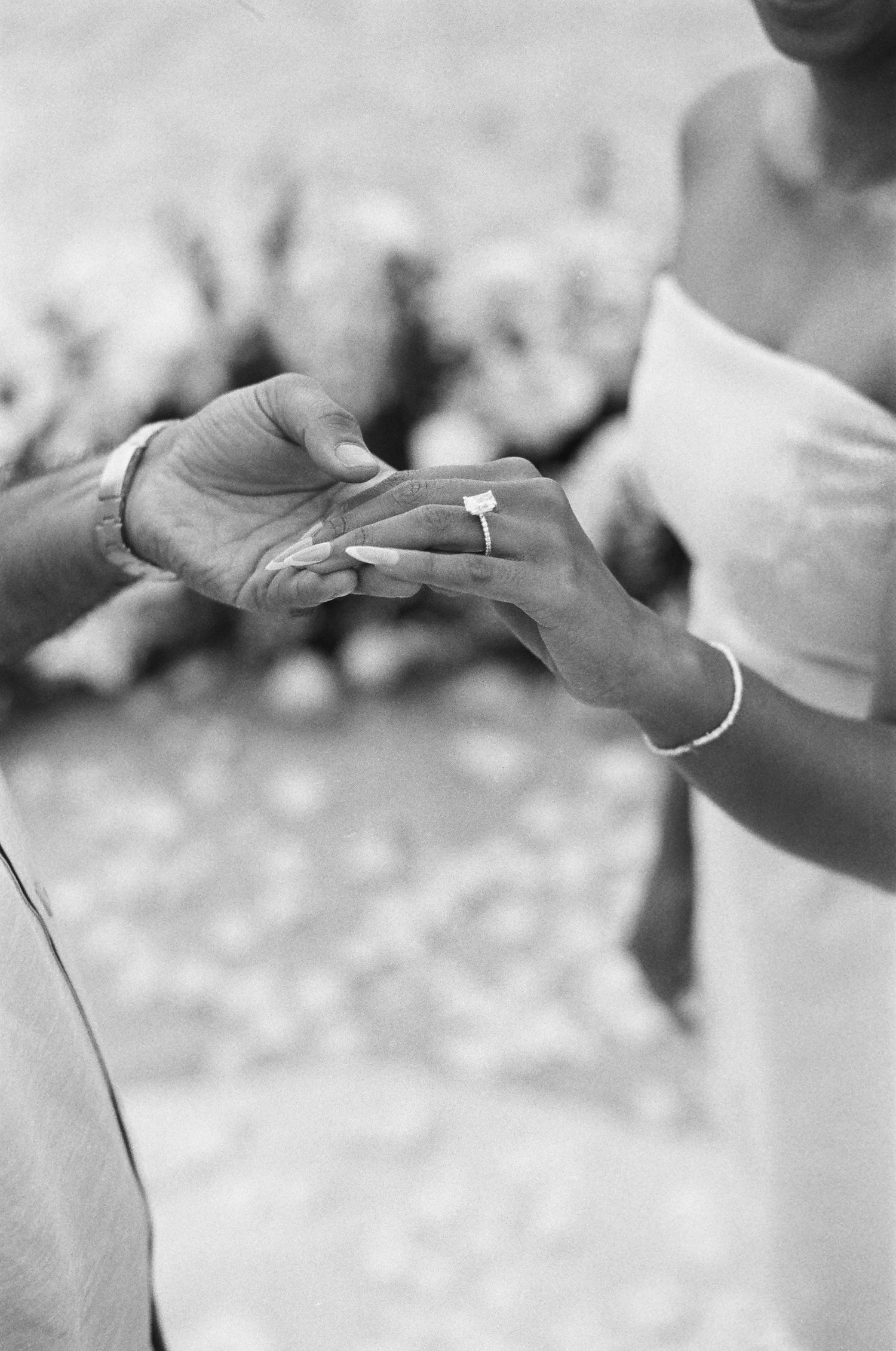 Close-up black and white photo of hands exchanging wedding rings during a ceremony.
