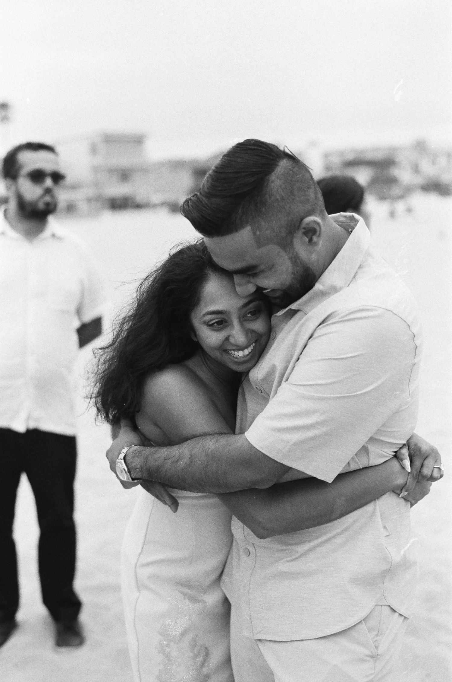 A loving embrace shared between a couple during a beach celebration.