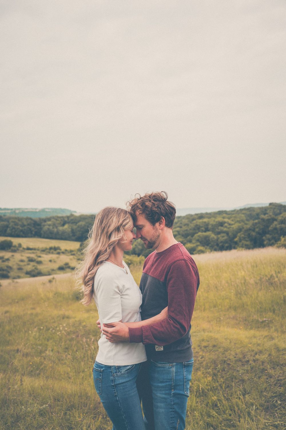 Couple sharing an intimate moment together in a golden grassy field at sunset.