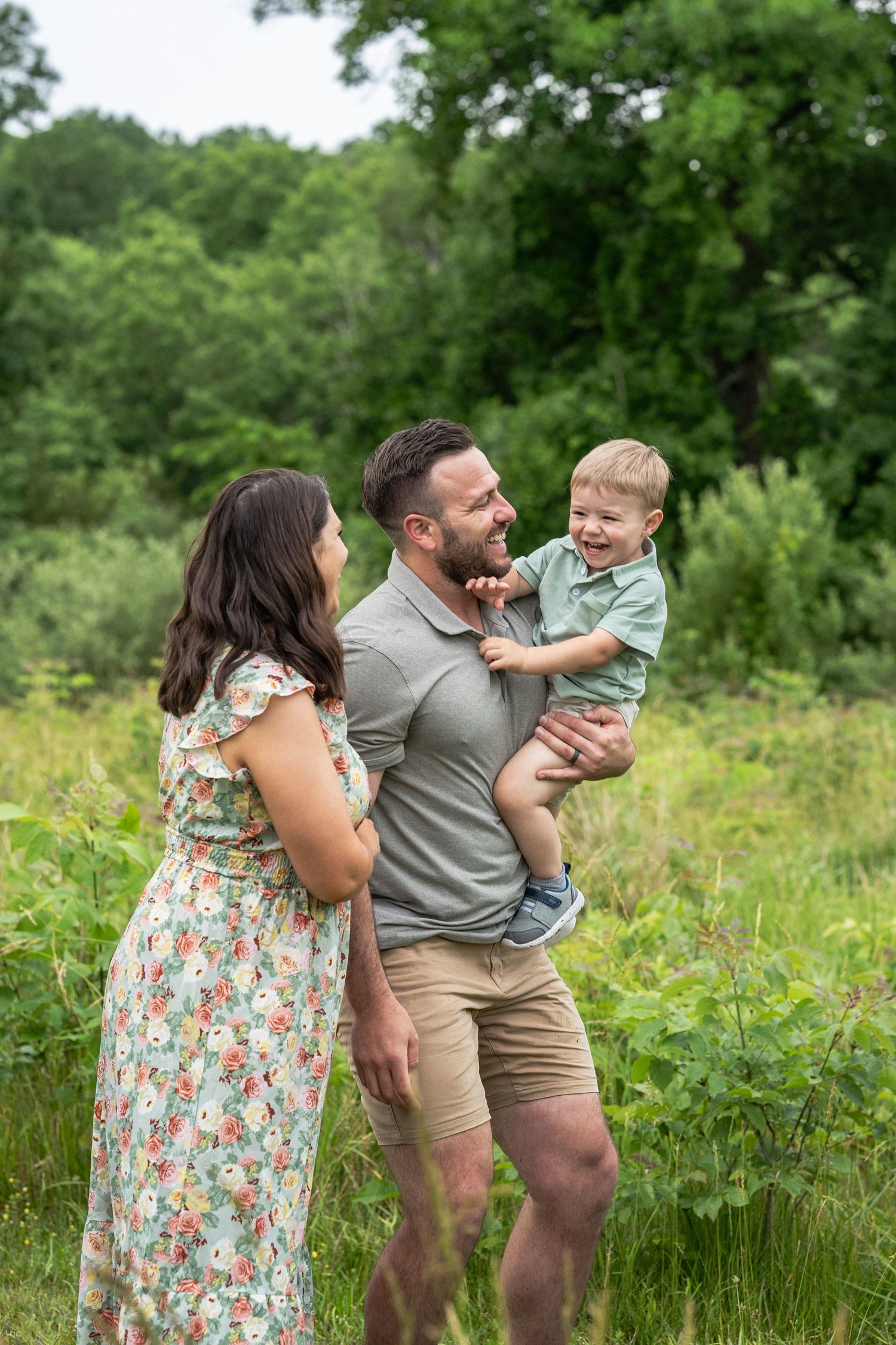 A family shares joyful moments together outdoors in a lush green field on a summer day.