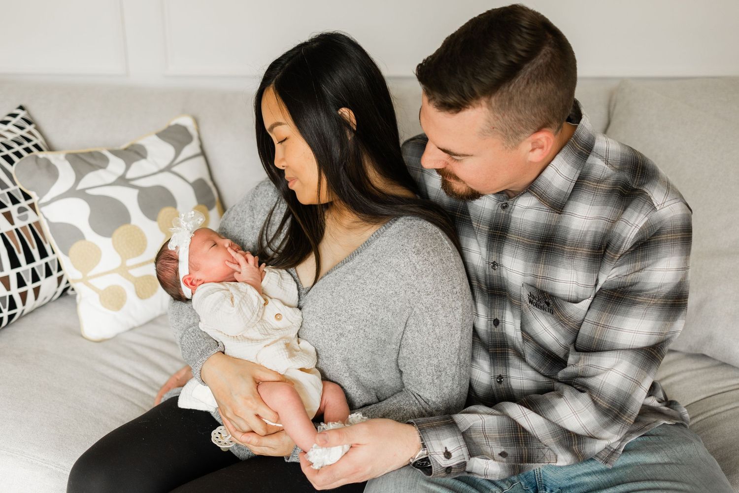 A family shares an intimate moment together on a gray couch in their living room.