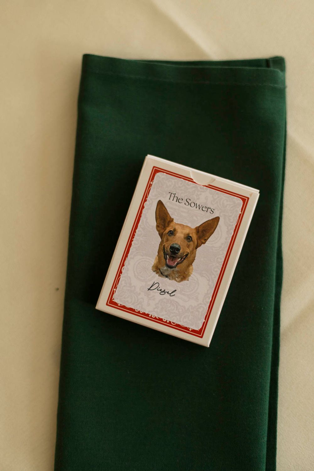 Playing card with German Shepherd dog illustration on dark green fabric napkin.