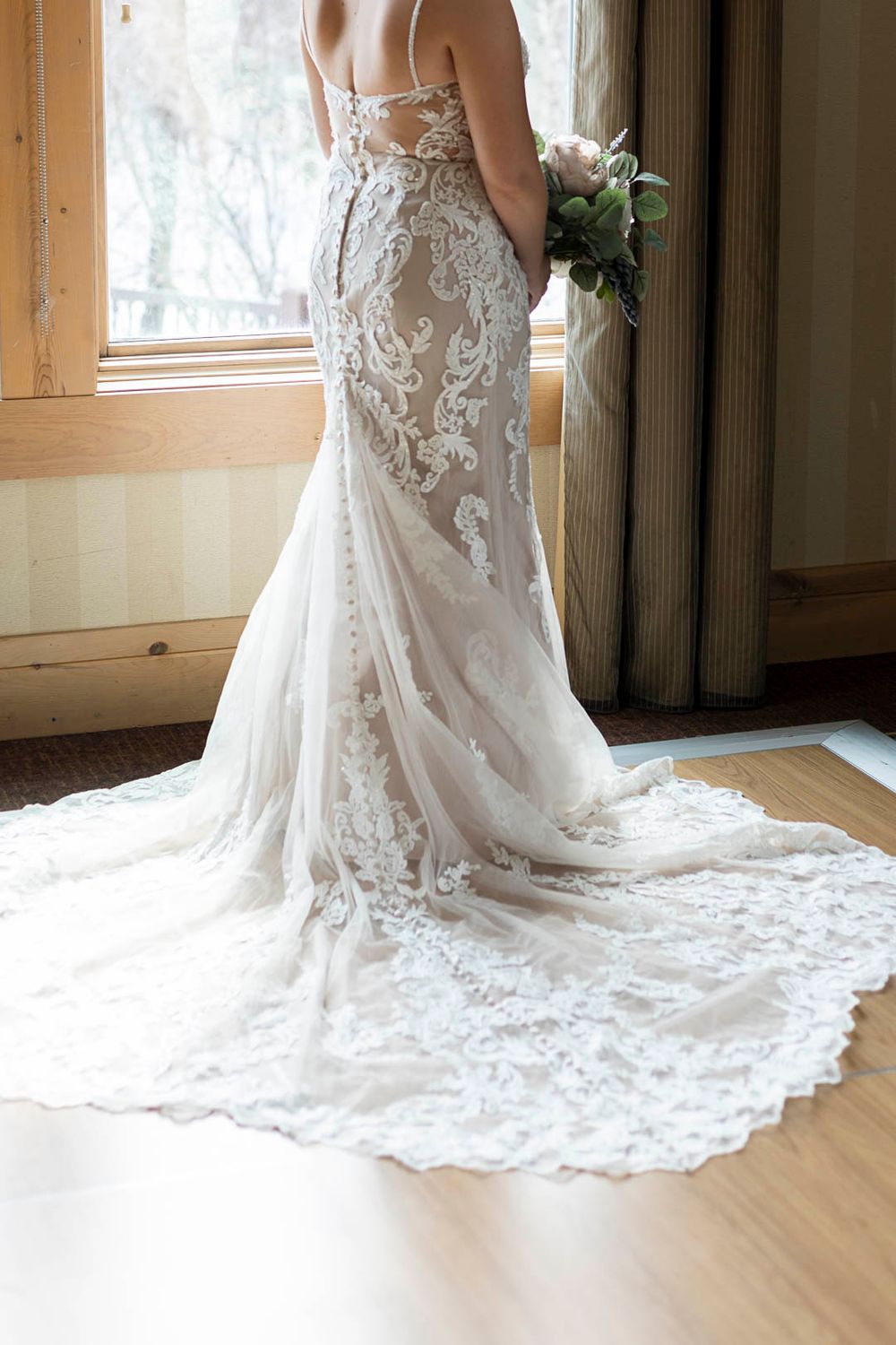 Detailed back view of white lace wedding dress with dramatic cathedral train.