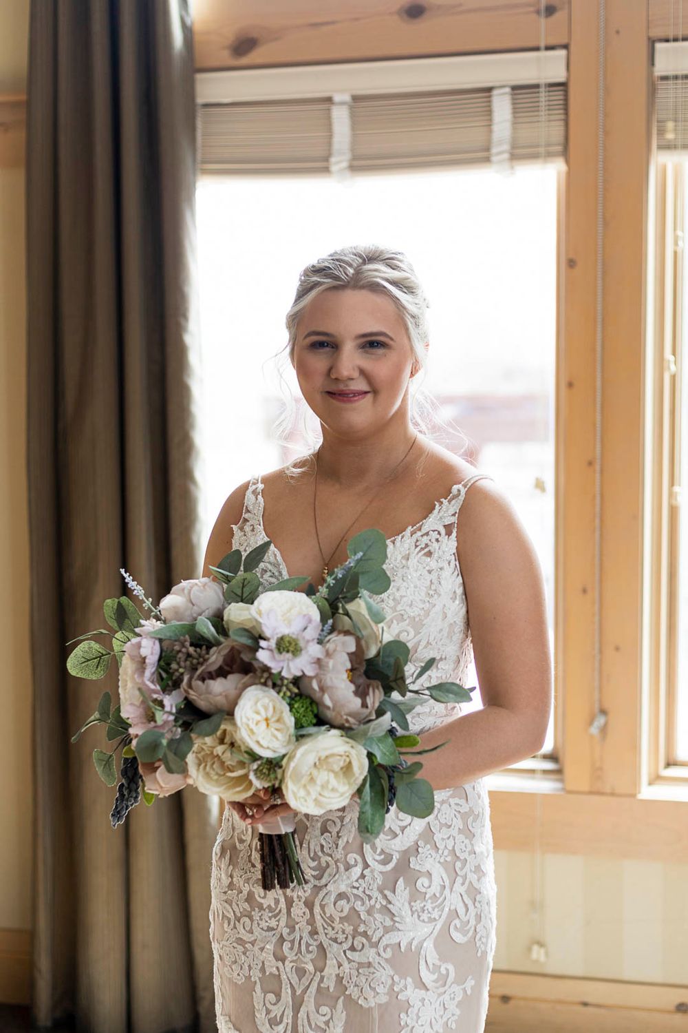 Elegant bridal portrait with white and blush bouquet by window.