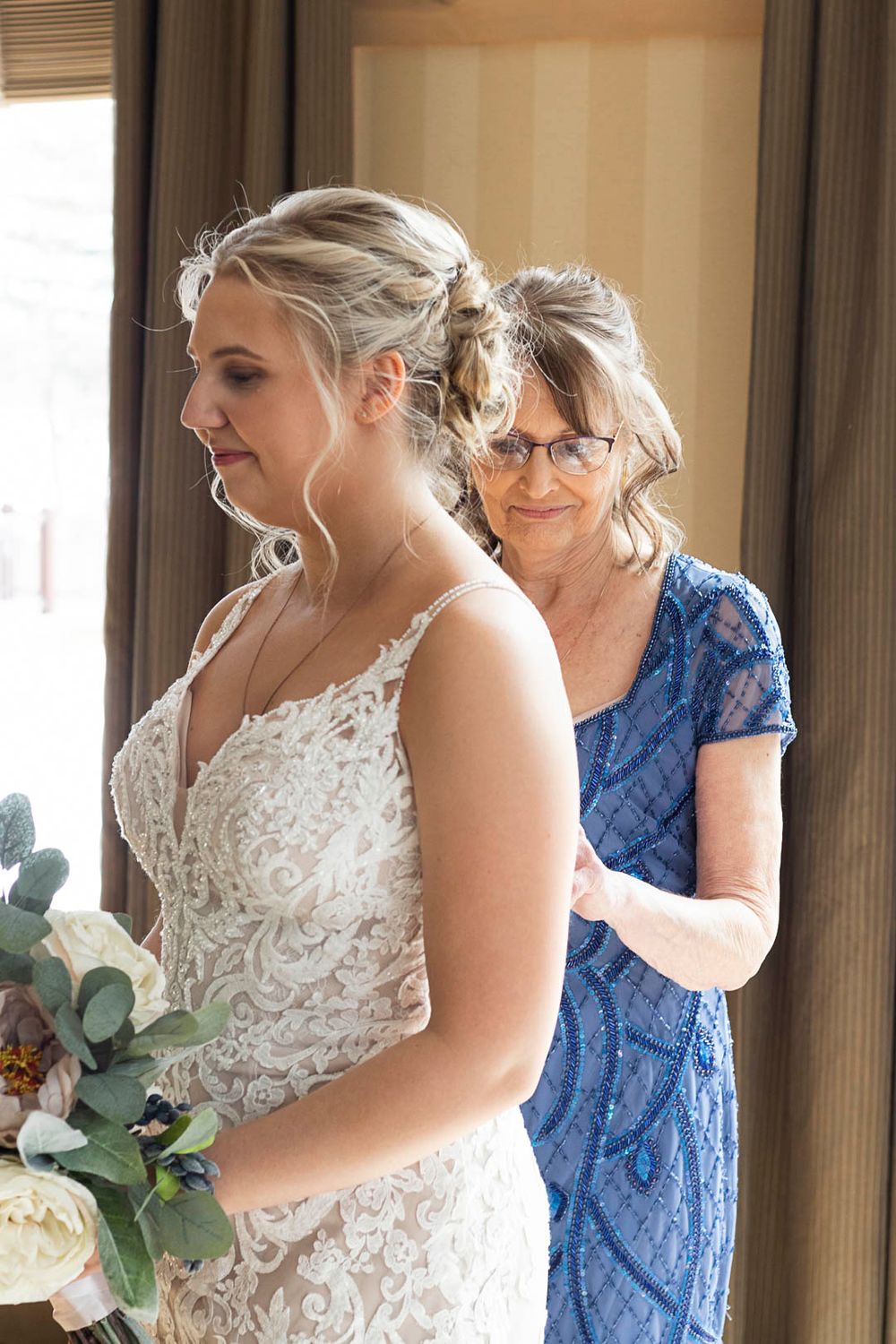 Wedding preparation moment with elegant lace gown and blue dress.