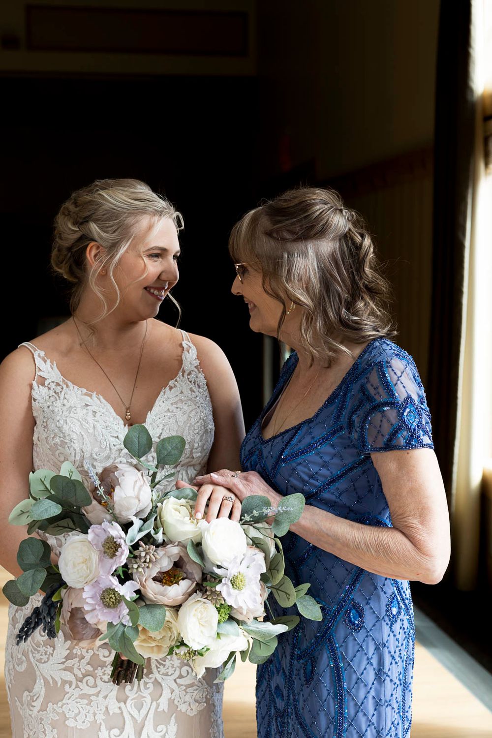 An intimate moment shared between two women in lace dresses with a white floral bouquet.