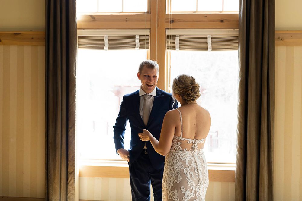 A tender wedding moment captured through a doorway with natural window light.