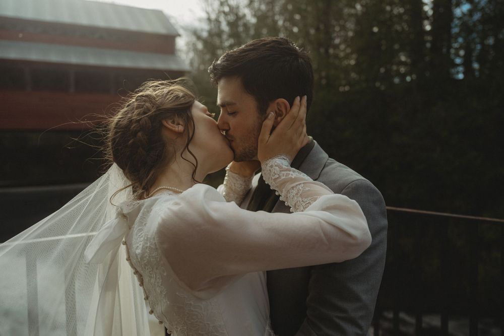 An intimate moment captured outdoors with soft natural lighting and brick building backdrop.