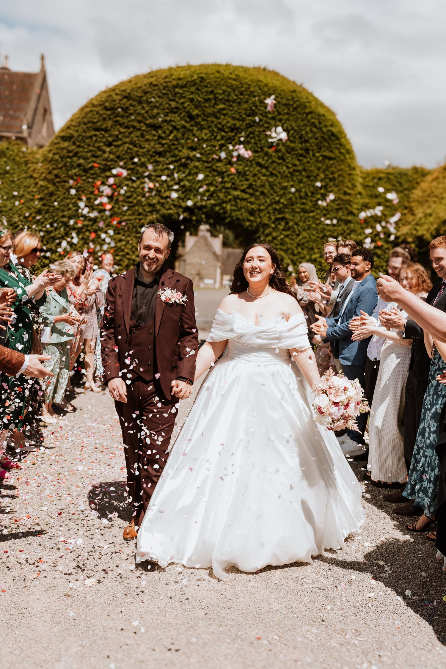 A series of five connected wedding photos showing guests throwing confetti during a celebration with round hedges in the background.