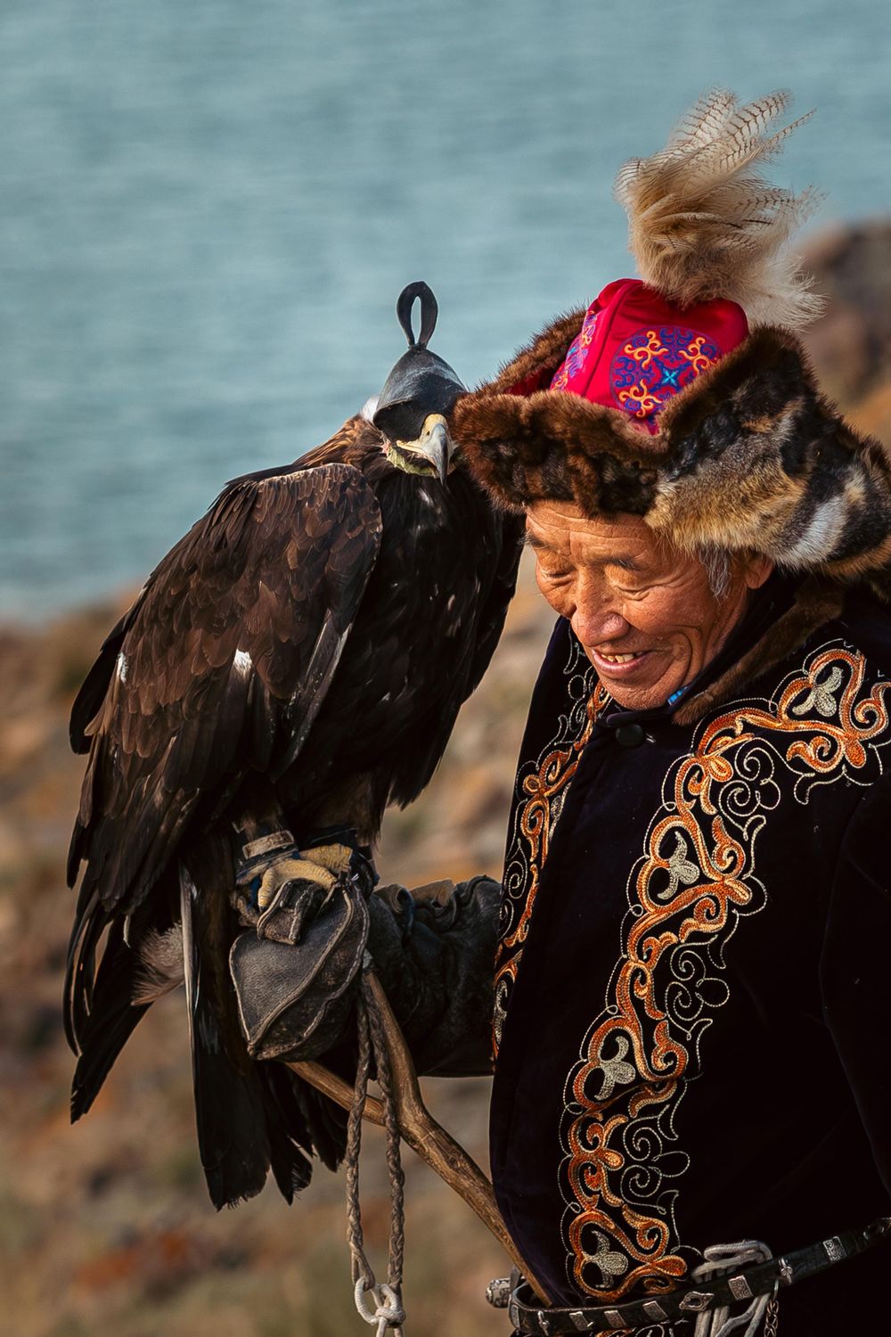 A traditional eagle hunter in ornate cultural dress holds a majestic bird of prey.