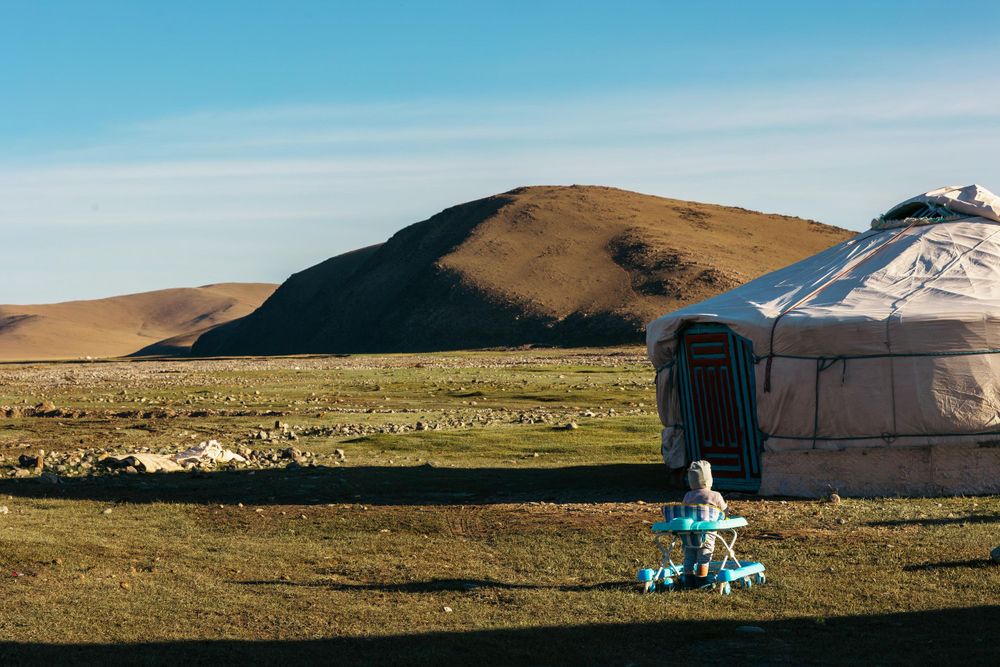 A traditional yurt stands against rolling hills in the Mongolian grasslands.