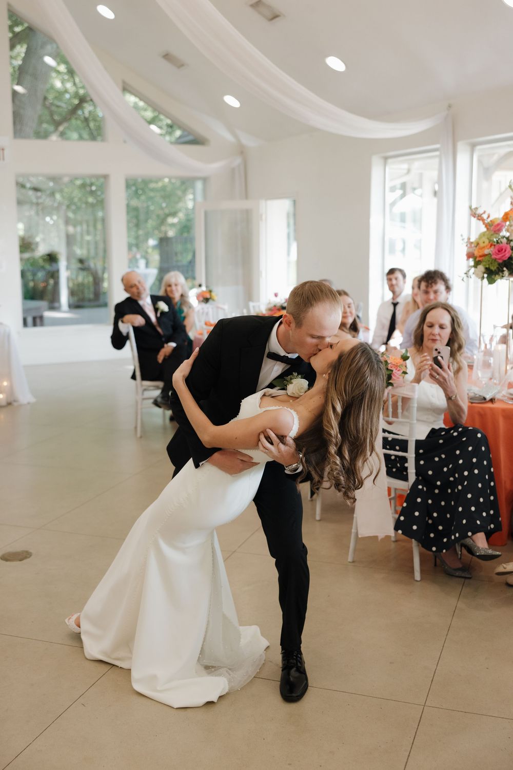 Romantic sequence of a couple sharing a dance dip during their wedding celebration in an elegant white venue.