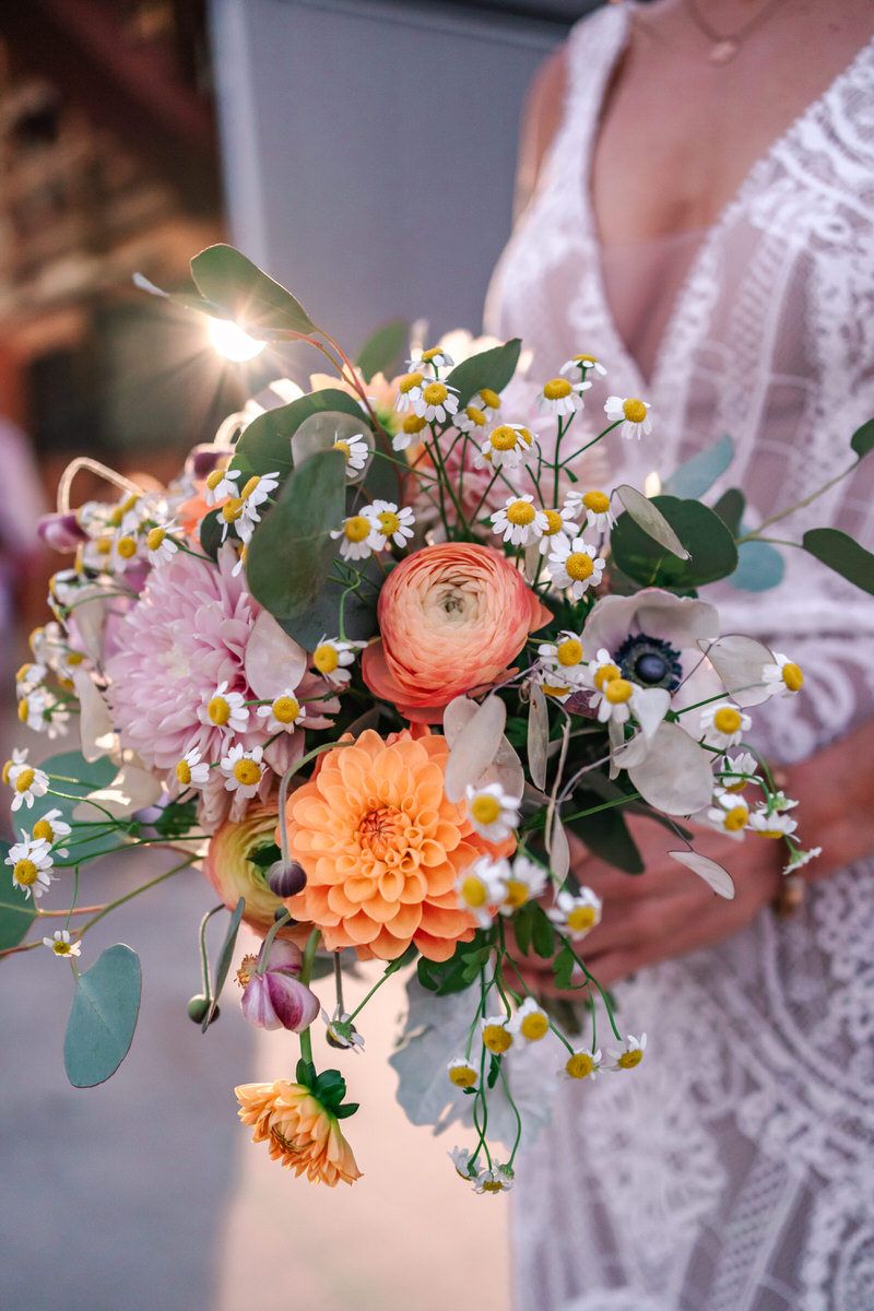 A bouquet held by the bride at dusk with a spotlight shining behind it.