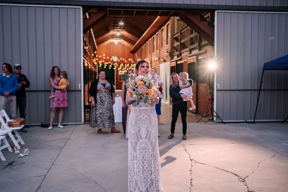 A bride gets ready to throw flowers during the bouquet toss at a back yard DIY wedding in South Haven, Michigan.