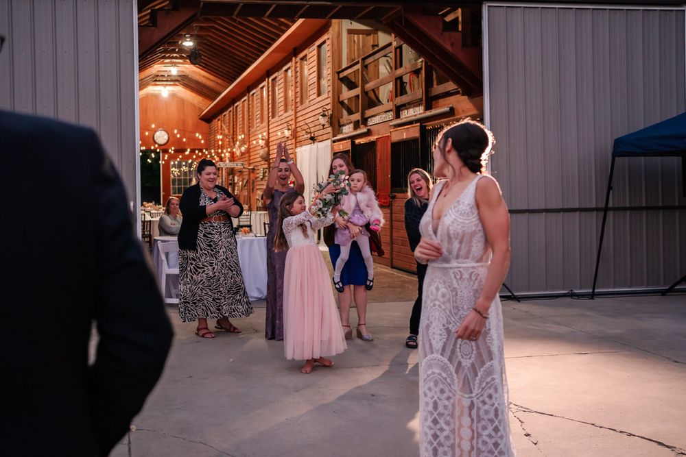 The bride looks back to see who caught her flowers at a DIY backyard wedding reception in South Haven, Michigan.