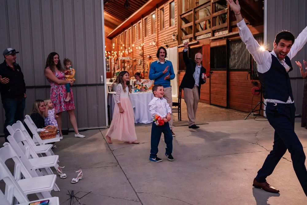 The groom celebrates the catch of a small toss-bouquet at end of the night in a small backyard wedding reception.
