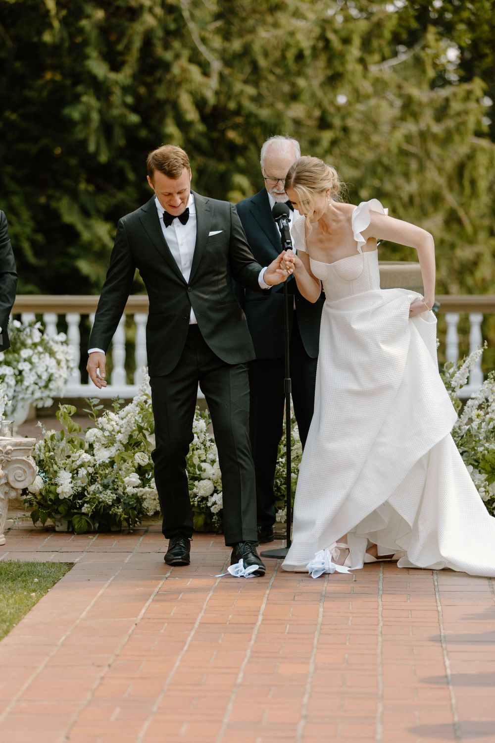 A joyful moment during a wedding ceremony as the couple walks together on a terra cotta tile patio.